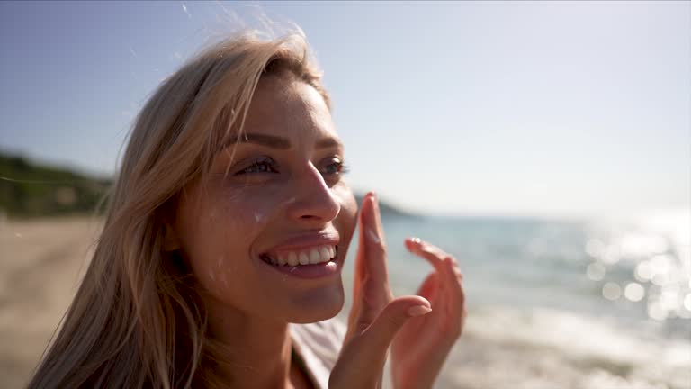 Young woman applying sunscreen at the beach