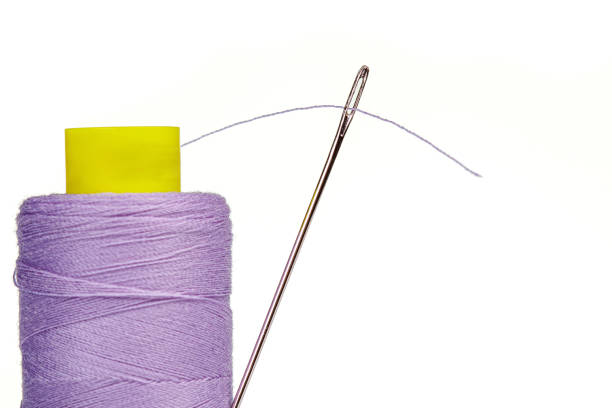 matassa macro di fili colori viola con un ago su sfondo bianco - thread needle sewing isolated foto e immagini stock