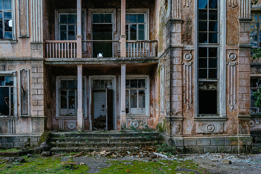 Overgrown by plants abandoned ruined houses at ghost-town. Green post-apocalypse concept.