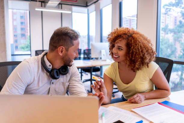 istock Diverse young colleagues flirting at the office while working on an idea at their place of work in a coworking office 1457193230