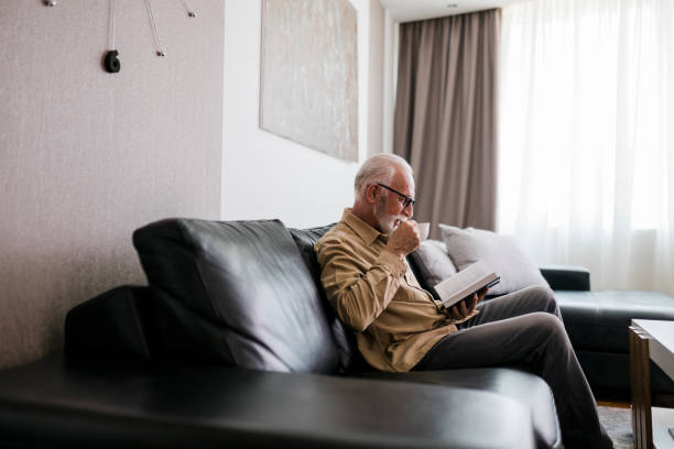 istock Senior man resting at home, drinking coffee and reading book 1457195640