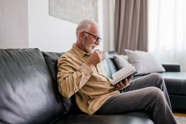 istock Senior man resting at home, drinking coffee and reading book 1457195786