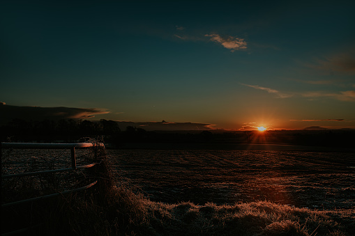 A wide shot of a frosty landscape during sunrise / sunset.