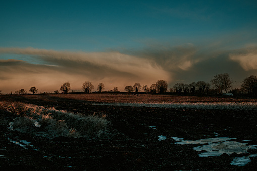 A wide shot of a frosty landscape during sunrise / sunset.