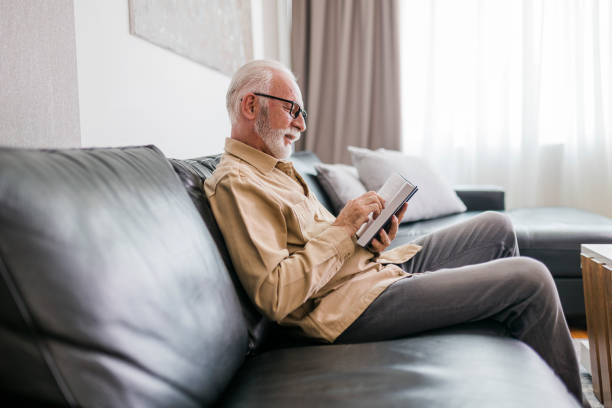 istock Senior Man reading book at home 1457196418