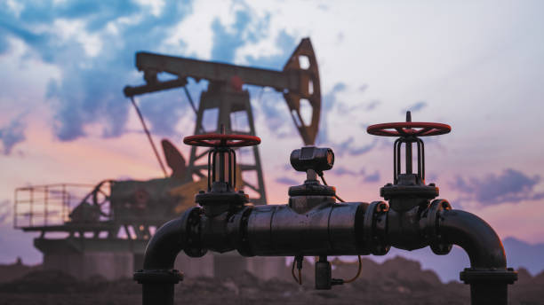 Gas Pipeline In Front Of The Oil Pump Gas pipe and pump jack silhouette against a sunset sky. north sea oil and gas stock pictures, royalty-free photos & images