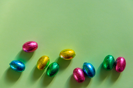Easter chocolate eggs in foil on green background. Top view