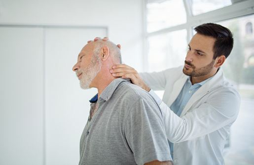 Closeup side view of a mature man having medical exam. The doctor is examining patient's neck for symptoms of arthritis and osteoporosis.