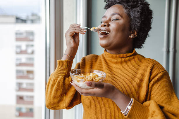 Happy African American woman eating cereals for breakfast at home stock photo
