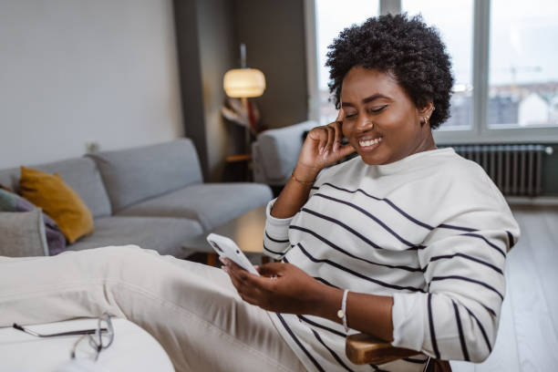 istock A young African woman using a smart phone and relaxing at home 1457204526