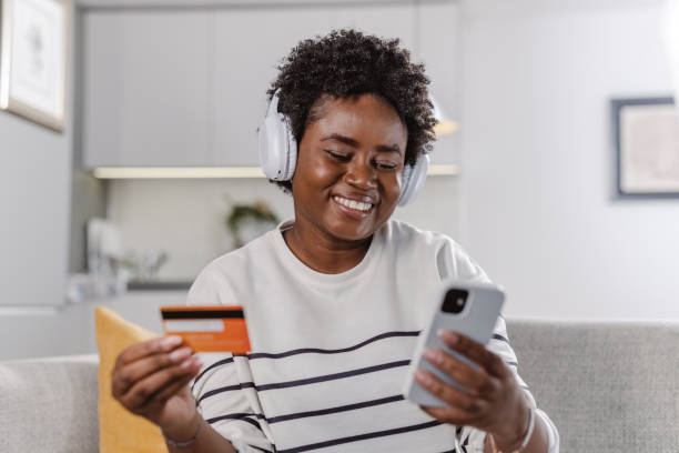 istock Young African-American woman using online services to perform e-commerce activity 1457204631