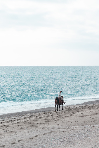 Photo of a man riding a horse at the beach