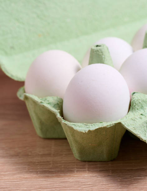 istock Fresh whole white eggs in green paper packaging on a wooden table 1457208993
