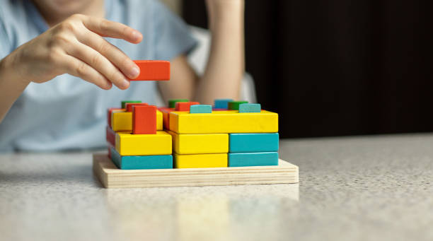 Close-up of children's hands playing with an educational multi-colored puzzle toy made of environmentally friendly wood material stock photo