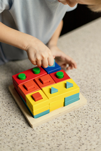 A child plays an educational puzzle toy made of environmentally friendly wood material