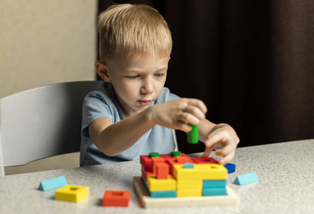 A child plays an educational puzzle toy made of environmentally friendly wood material stock photo