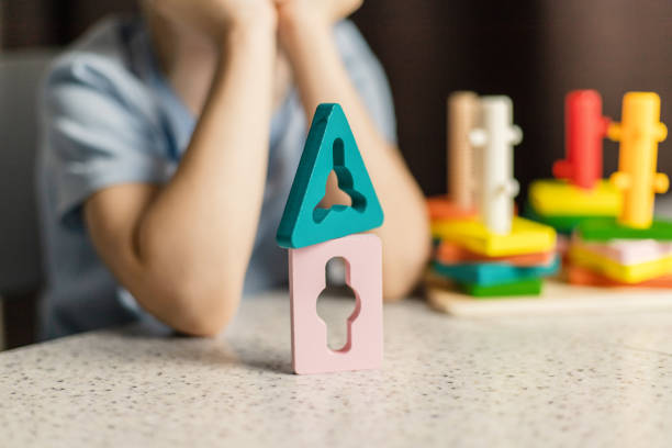 Close-up of wooden parts of a multi-colored educational toy against the background of children's hands stock photo