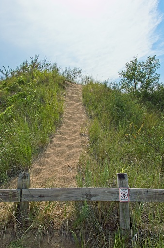 Sand dunes, beach grass and cloudscape at Indiana Dunes National Park. Footprints through the high dunes on the south end of Lake Michigan provide scenic views, birdwatching and beach activities.