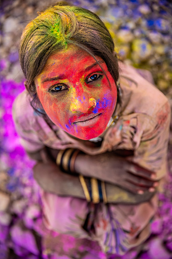 Happy Gypsy Indian children playing happy holi on sand dunes in desert village, Thar Desert, Rajasthan, India. Color powders are on their faces and clothes. Holi is a religious festival in India, celebrated, with the color powders, during the spring.