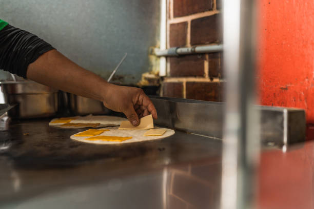 istock Cook adding some cheese to melt inside a mexican taco 1457217633