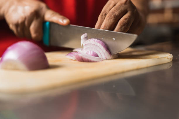 istock Cook using a knife to cut onions in a kitchen 1457218877