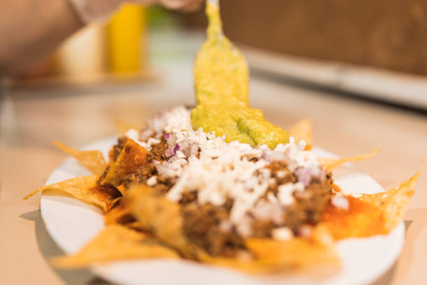 Preparing Mexican food, delicious nachos, seasoned with chili based sauce.