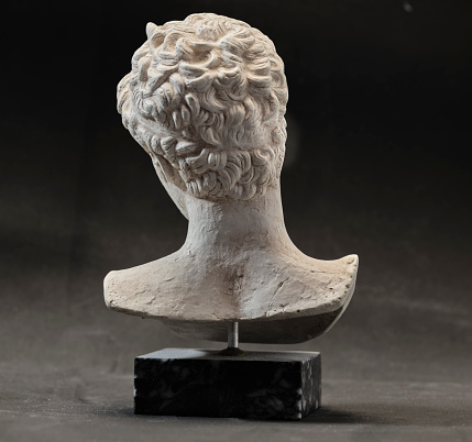 An ancient statue of a young man from ancient Greece presumed to be a  philosopher or poet, severe and sad. Small reproduction of original