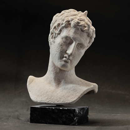 An ancient statue of a young man from ancient Greece presumed to be a  philosopher or poet, severe and sad. Small reproduction of original