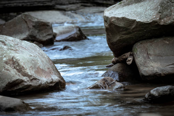 Close up to the river flowing between rocks, beautiful stone textures carved by water, background out of focus in purpose, in New Taipei City, Taiwan.
