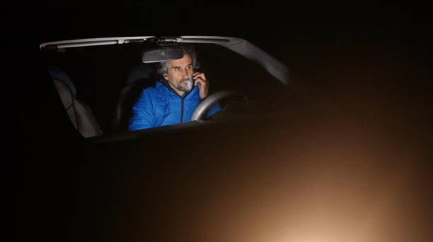 istock Man in car talking on phone at night. 1457229814