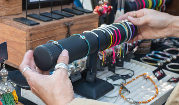 la vendedora de mano femenina arregló joyas en la mesa que preparaba vender a los clientes en el mercado local de tailandia. - selling merchandise craft thailand fotografías e imágenes de stock