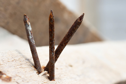 rusty nails stuck in wood with bokeh background