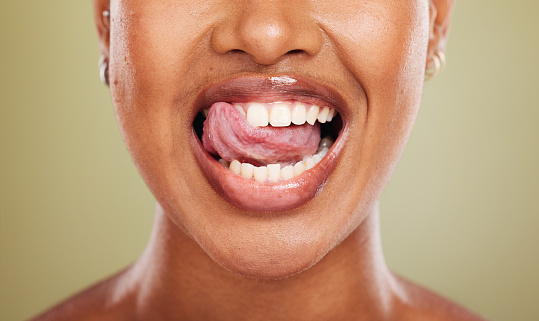 Tongue, teeth and african woman in closeup with lick, smile or happy for dental wellness in studio. Model, mouth or perfect teeth whitening for health, medical or beauty by background in healthcare