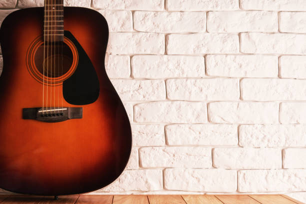 istock Wooden table with an acoustic guitar and white bricks background 1457236805