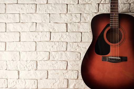 Wide banner with acoustic guitar with a white bricks background. Abstract music and sound backdrops. Copy space for text