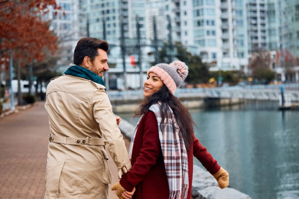 istock Happy couple holding hands while walking by a quay. 1457239797