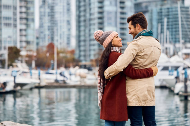 Embraced couple talking while enjoying on city quay.