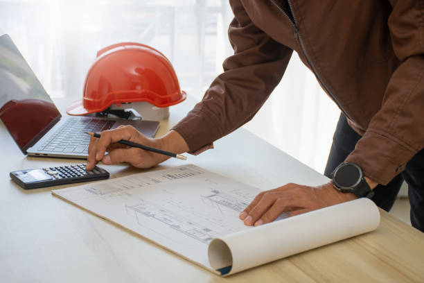 Architecture man work on blueprint and using calculator Architecture man work on blueprint and using calculator at office. autocad house plans stock pictures, royalty-free photos & images
