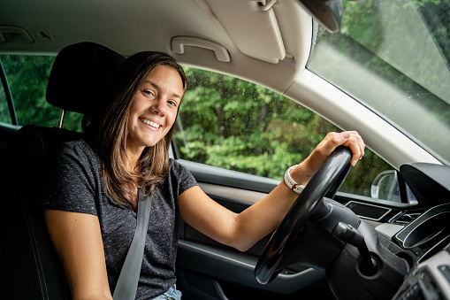 Happy young woman portrait behind the steering wheel in the car