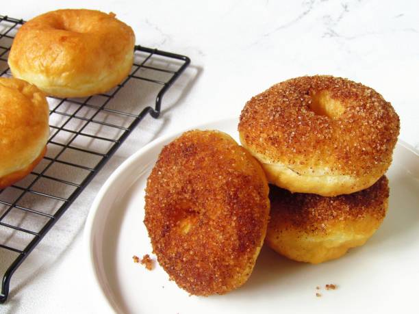 istock Potato donuts with sugar and cinnamon topping on a white plate, o a white background 1457247959