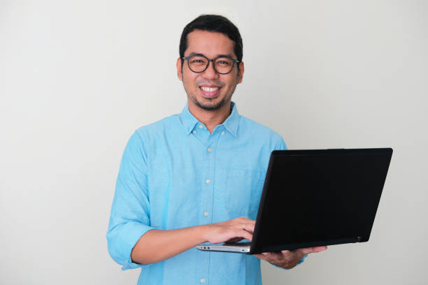 istock Adult Asian man smiling confident while holding a laptop 1457248376