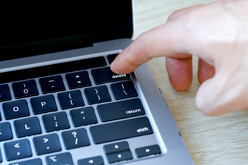Con el dedo del usuario de la computadora, presiona el botón de borrar en el teclado del ordenador. photo