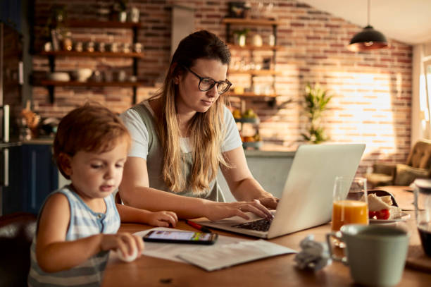 istock Young woman using the laptop while her son is using her phone 1457249804