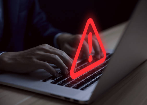 istock Businessman using laptop warning about dangerous problem showing warning triangle and red exclamation mark icon 1457250392