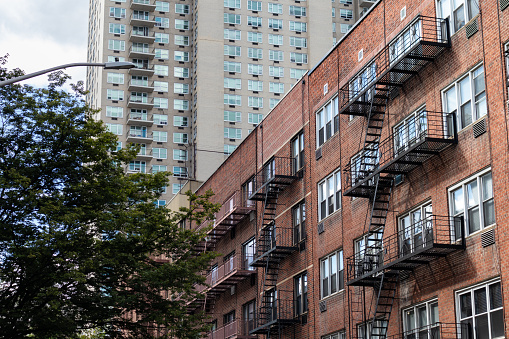 A row of old brick apartment buildings with fire escapes along a residential street on the Upper East Side of New York City