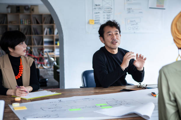 istock Designers in lively discussion at a table in their office. 1457254249