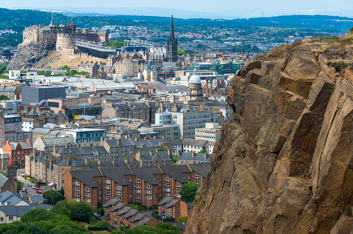 Rocky cliffs in the foreground,dominate the Scotland's capital city,with famous landmarks, Edinburgh Castle set for the Royal MilitaryTattoo,during Fringe Festival,the Hub and St. Mary's Cathedral.