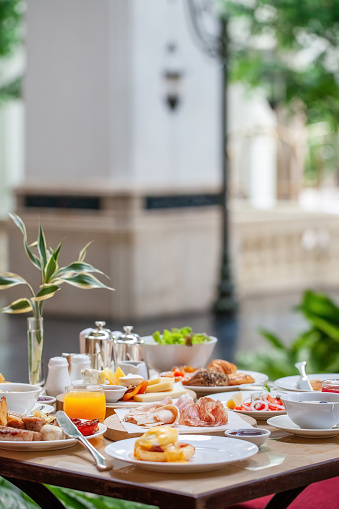 Table full of various fresh food in luxury modern restaurant in hotel. Delicious dishes, including fruits, pastries, cooked meals on table. Restaurant setting, modern decor, sophisticated atmosphere