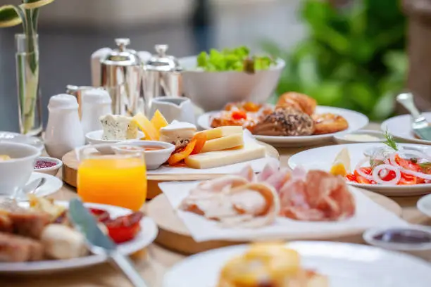 Table full of various fresh food in luxury modern restaurant. Delicious dishes, cold cuts, salmon, omelette, pastries, juices, cheese. Delicious and lavish breakfast or morning meal in high-end hotel