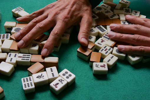 Elderly people playing mahjong, indoor gamble activity at home during spring festival.